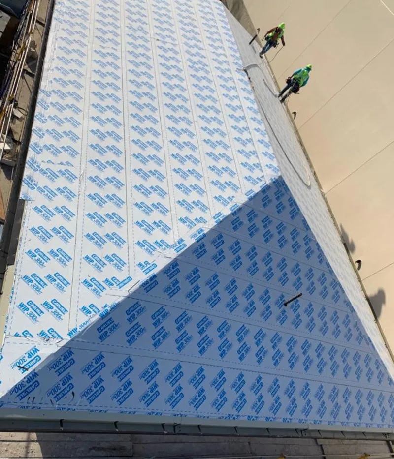 Professional roofers installing underlayment on a metal roof in Newport Beach